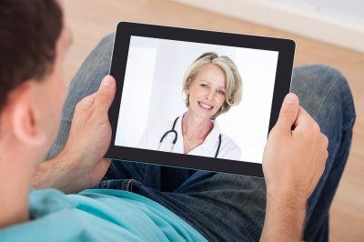 Man having video chat with female doctor on digital tablet at home